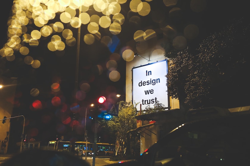 Photograph of billboard displaying 'In design we trust'