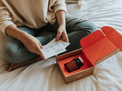 person opening subscription delivery sitting on bed