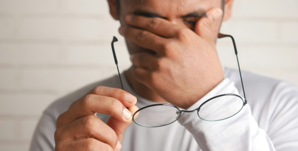 A man rubs his eyes in the universal gesture of I have a headache.