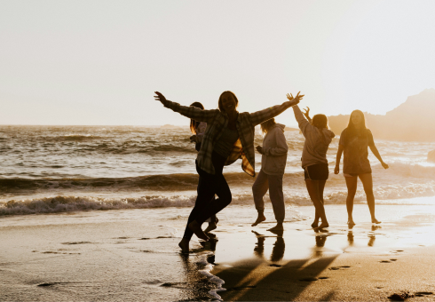 A group of Gen Zalpha playing on a beach at sunset