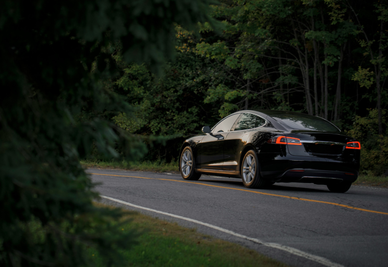 EV drives down wooded road