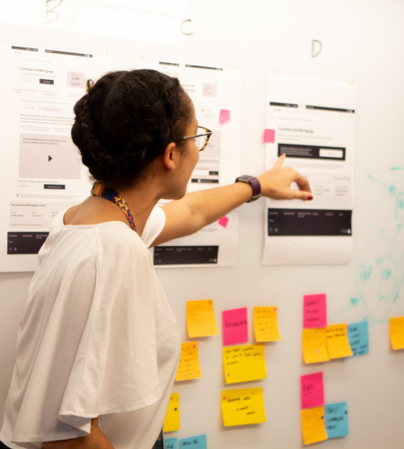 Woman at whiteboard pointing to printout as part of workshop