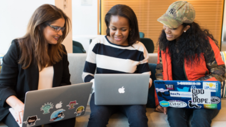 Three colleagues working together, sitting on a sofa with laptops